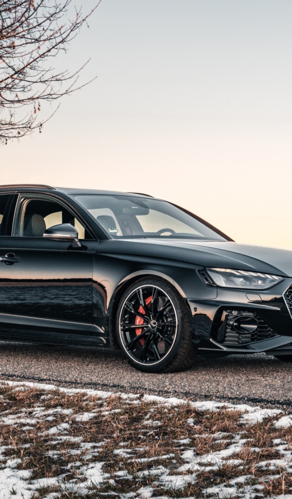 Черный автомобиль  Audi RS 4 Avant 2020 года на дороге у дерева