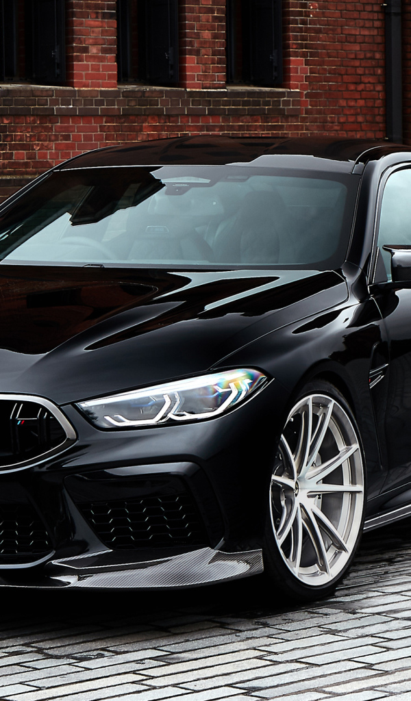 Дорогой черный автомобиль BMW M8 у стены