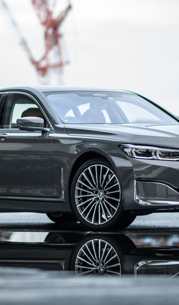 Серебристый автомобиль BMW 745e на мокром асфальте 