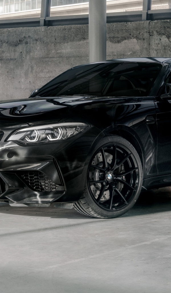 Черный автомобиль  BMW M2, 2020 года у бетонной стены