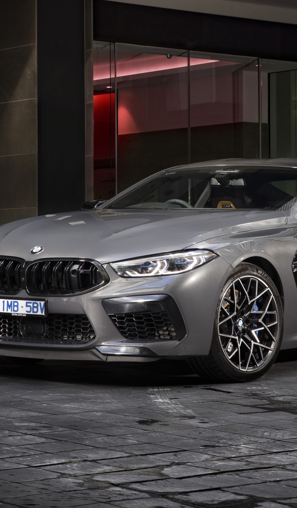 Серебристый автомобиль BMW M8 Competition Coupe 2020 года у здания 