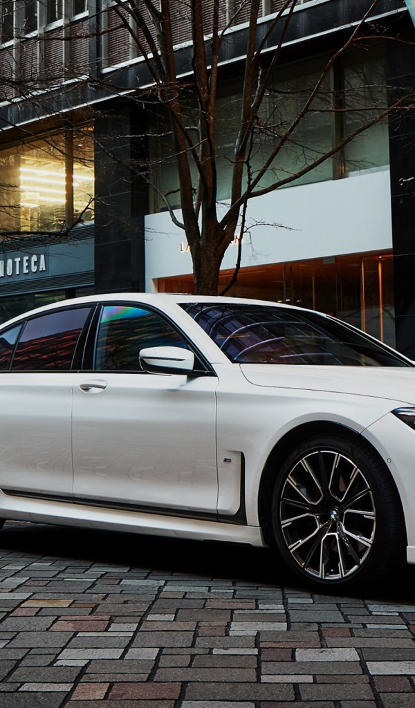 Белый автомобиль  BMW 740i M Sport 2020 года у кафе