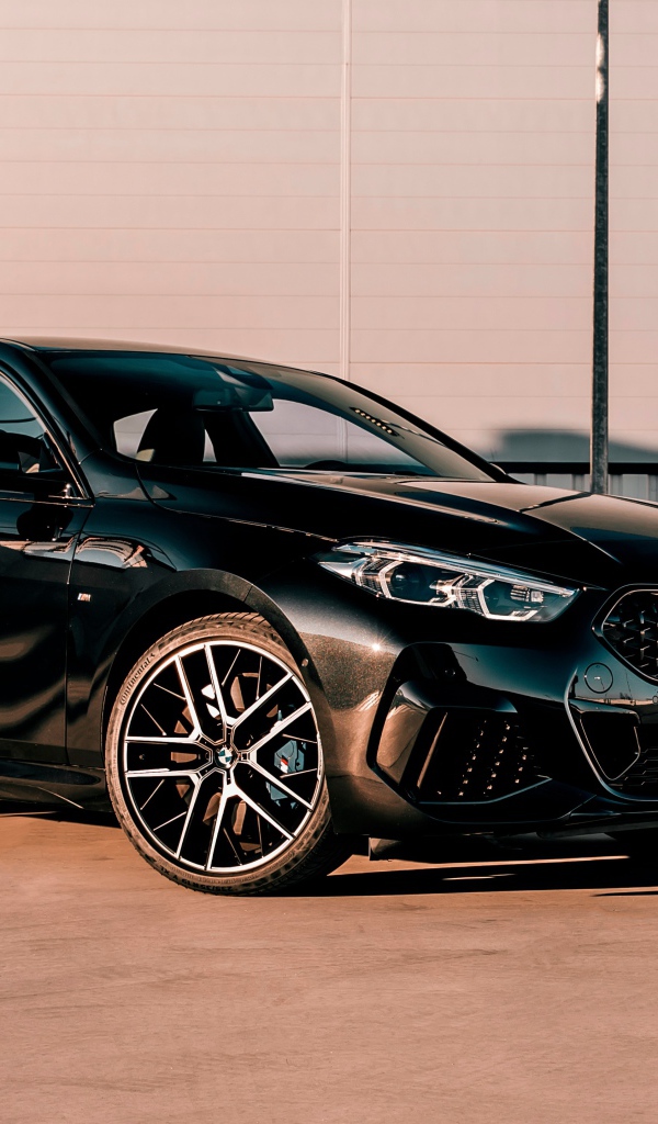 Черный автомобиль BMW M235i XDrive Gran, 2020 года у белого здания 