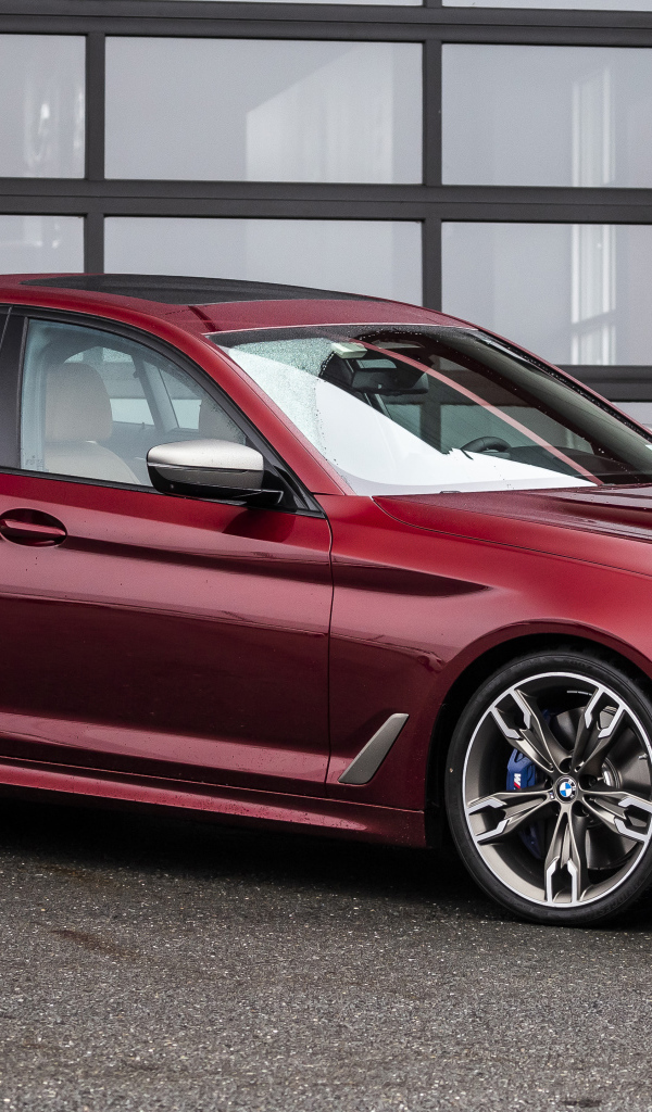 Красный автомобиль BMW M550i XDrive, 2021 года у гаража