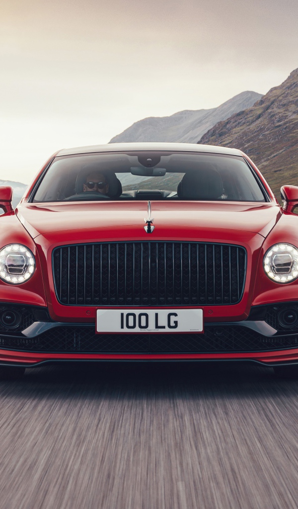 Красный автомобиль Bentley Flying Spur V8 2020 года на дороге в горах 