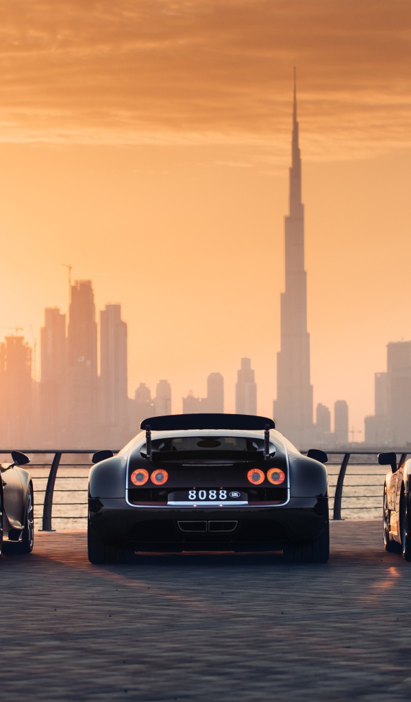 Три автомобиля  Bugatti Veyron и Bugatti Chiron на фоне заката