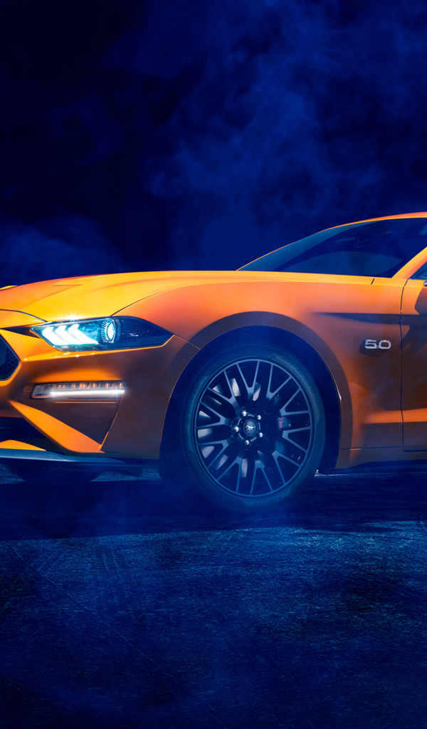 Оранжевый автомобиль Ford Mustang в дыму