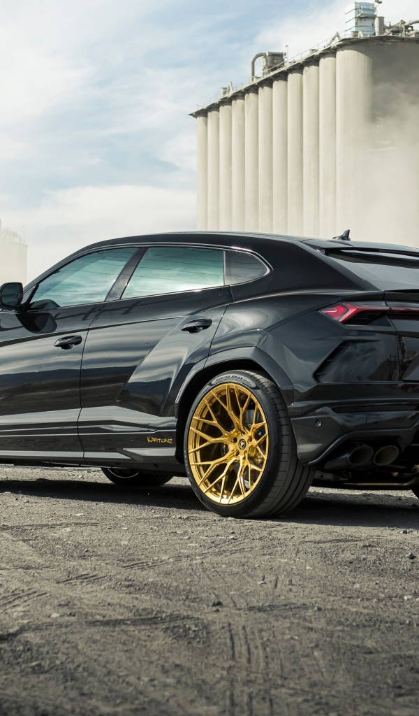 Черный внедорожник  Lamborghini Urus 2020 года на фоне завода вид сзади