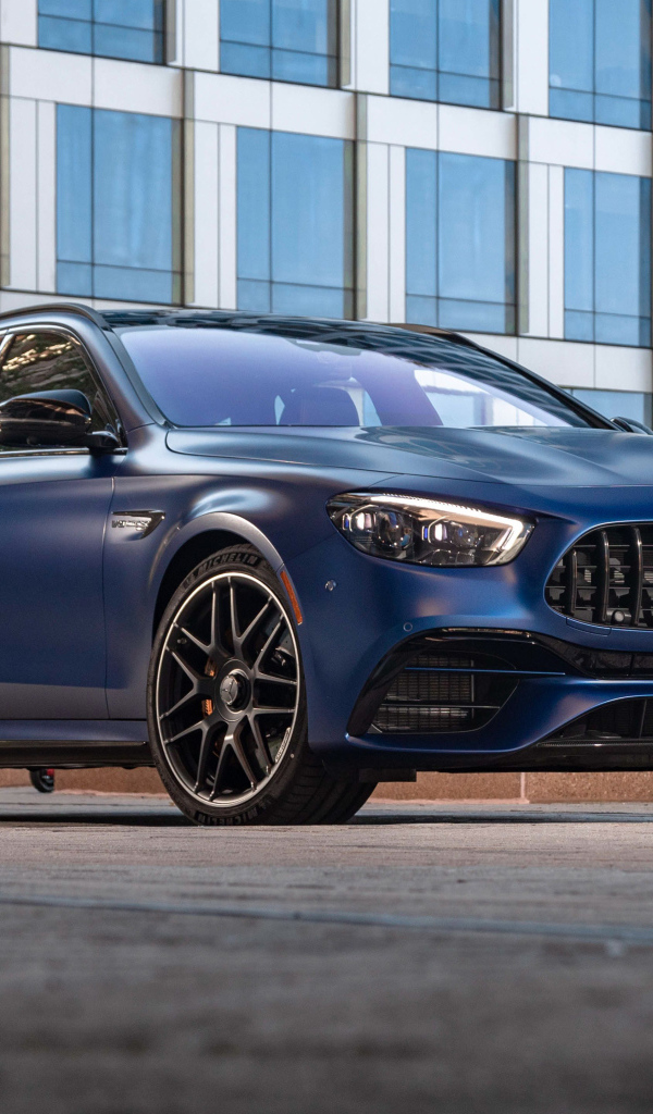 Синий автомобиль Mercedes-AMG E 63 S 4MATIC+, 2021 года на фоне дома