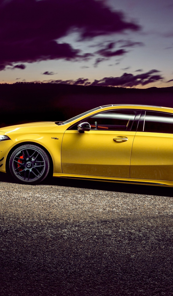 Желтый автомобиль Mercedes-AMG A 45 S, 2020 года на дороге в сумерках 