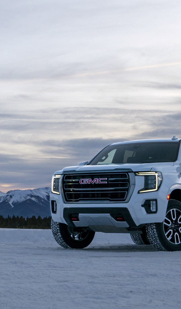 Белый внедорожник  GMC Yukon AT4, 2021 года на фоне заснеженных гор 