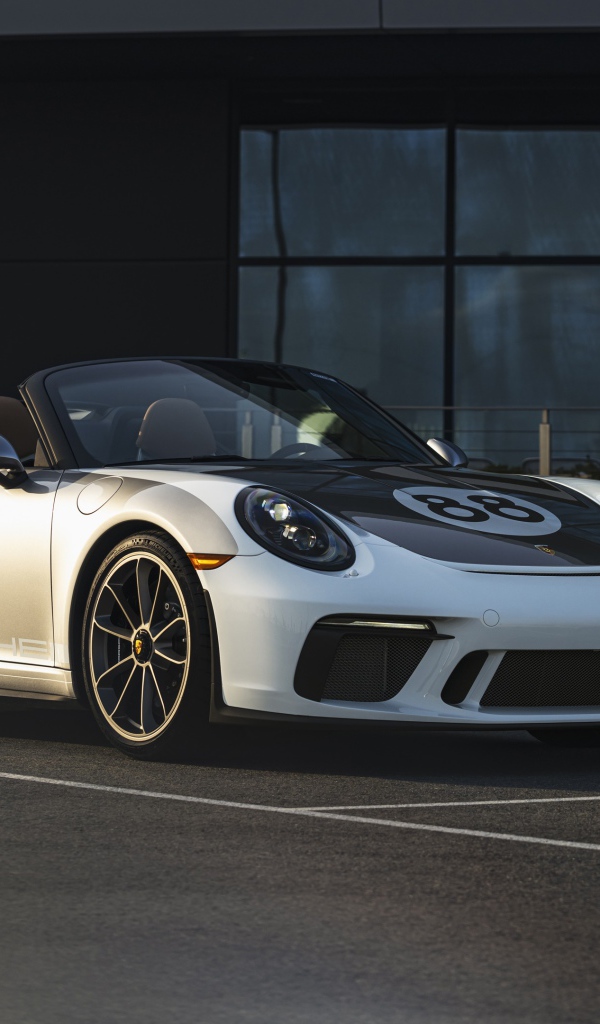 Спортивный автомобиль Porsche 911, 2019 года у стеклянного здания