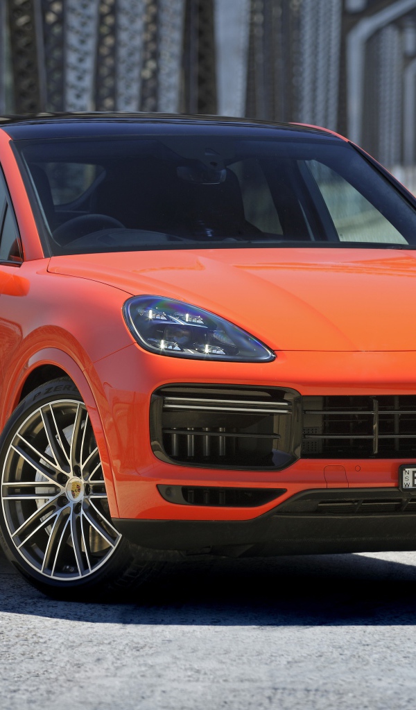 Оранжевый внедорожник Porsche Cayenne Turbo Coupe 2019 года на мосту