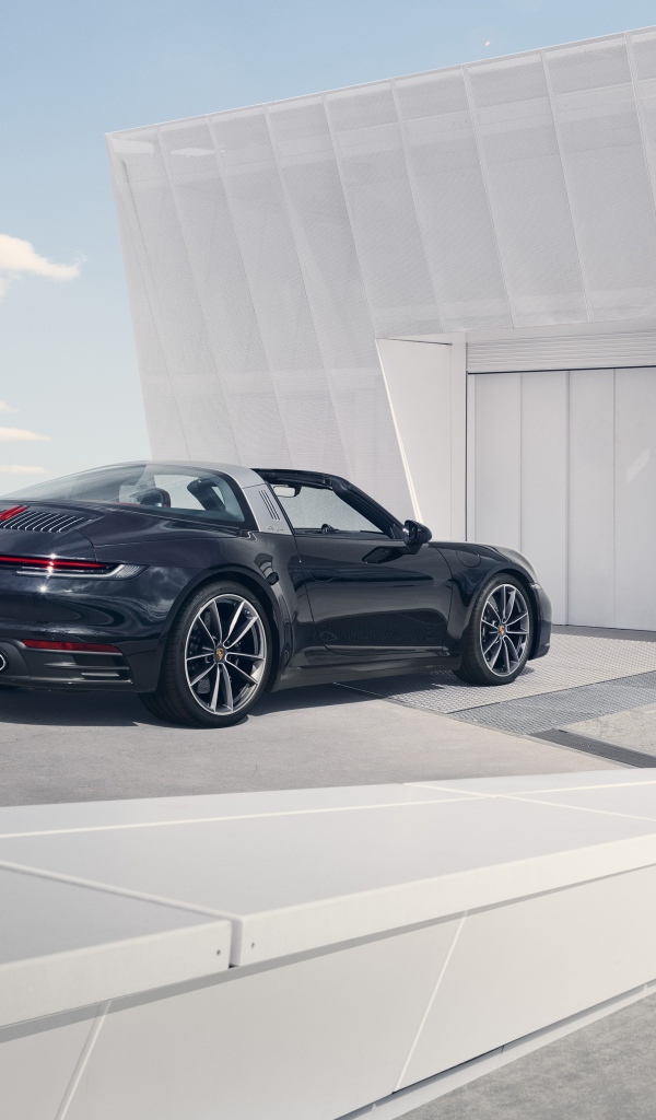 Черный автомобиль Porsche 911 Targa 4S 2020 года у гаража 