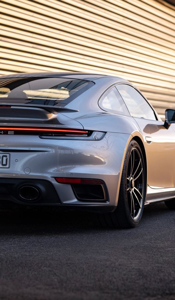 Серебристый автомобиль Porsche 911 Turbo S 2020 года у гаража