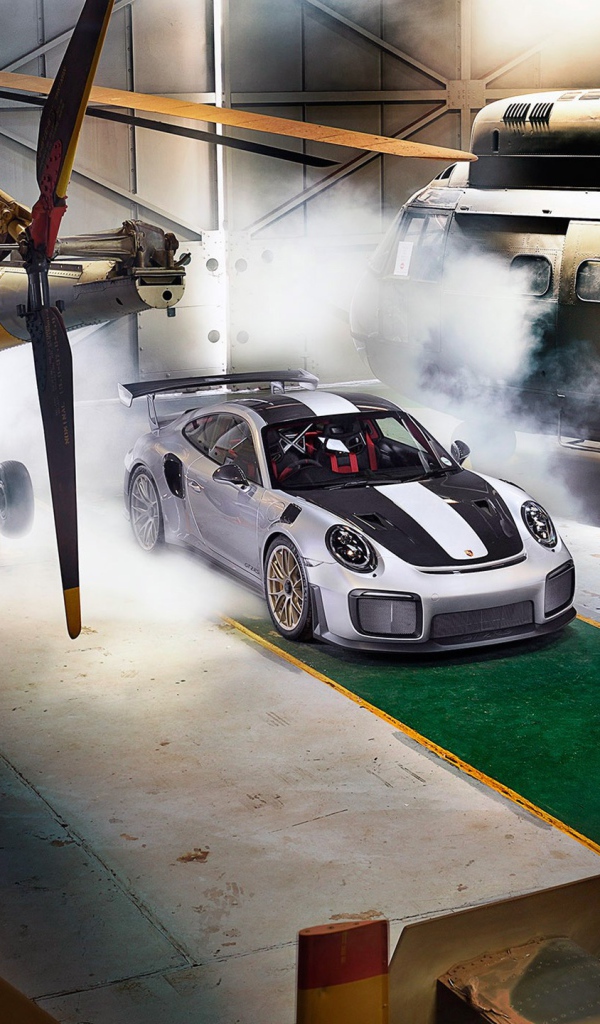 Автомобиль Porsche 911 GT2 RS в ангаре с вертолетами