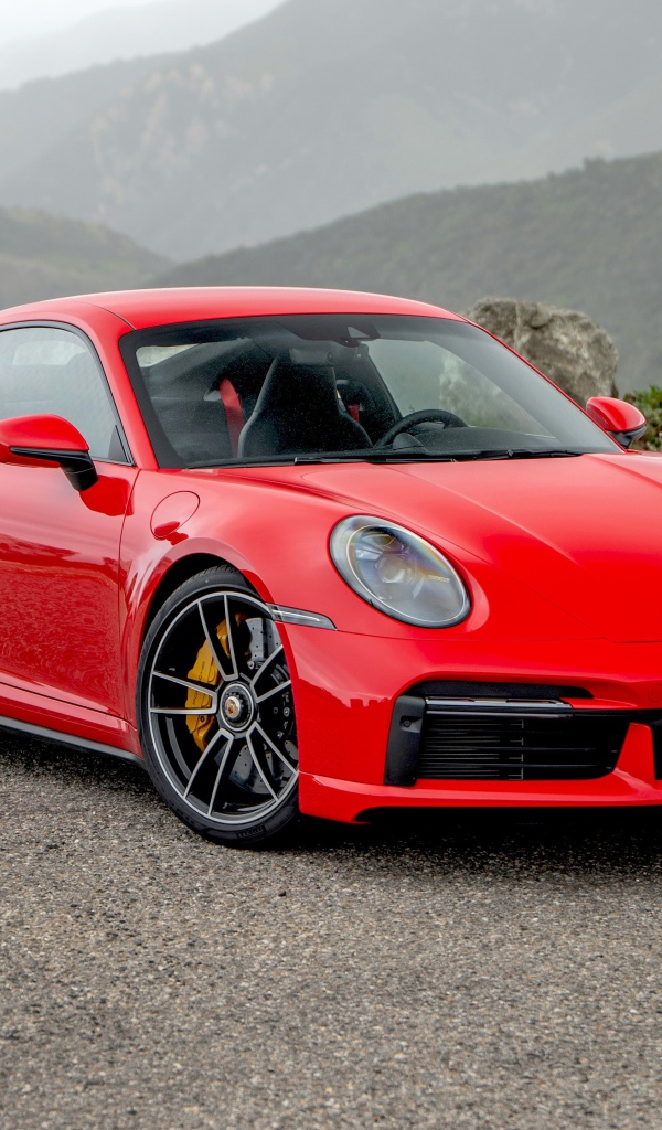 Красный автомобиль Porsche 911 Turbo S 2020 года на фоне гор 