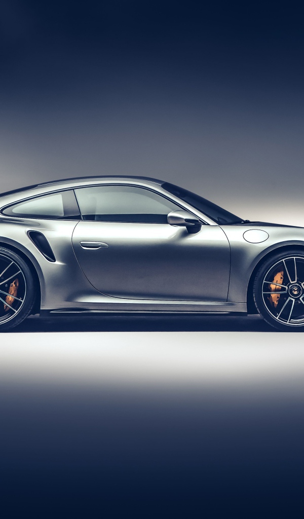 Серебристый автомобиль Porsche 911 Turbo S 2020 года вид сбоку на сером фоне