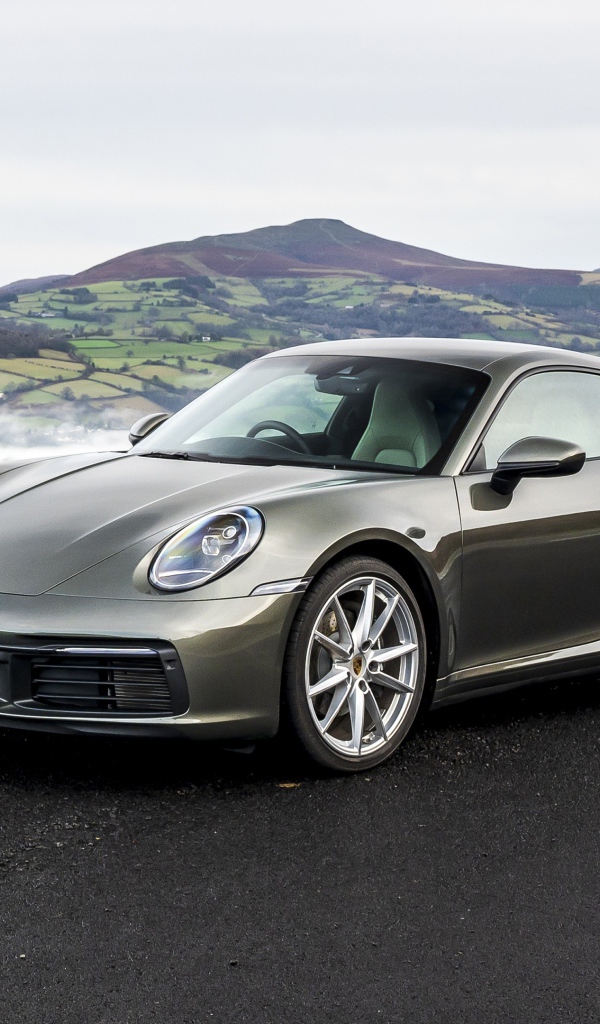 Серебристый автомобиль Porsche 911 Carrera на фоне холмов