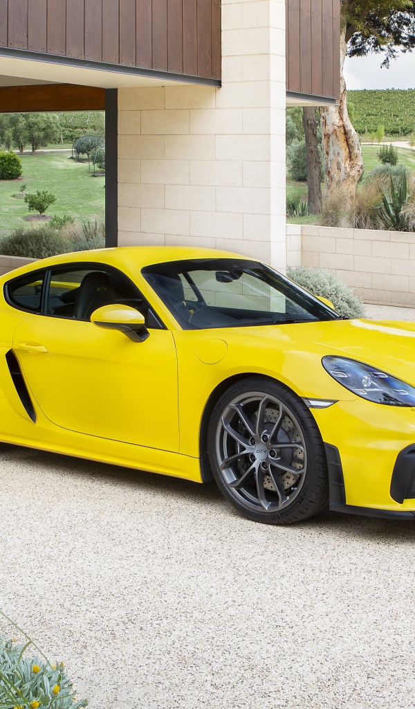 Желтый автомобиль Porsche 718 Cayman GT4, 2020 года у дома