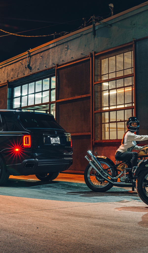 Черный автомобиль Rolls-Royce Cullinan, 2020 года у гаража с байкерами