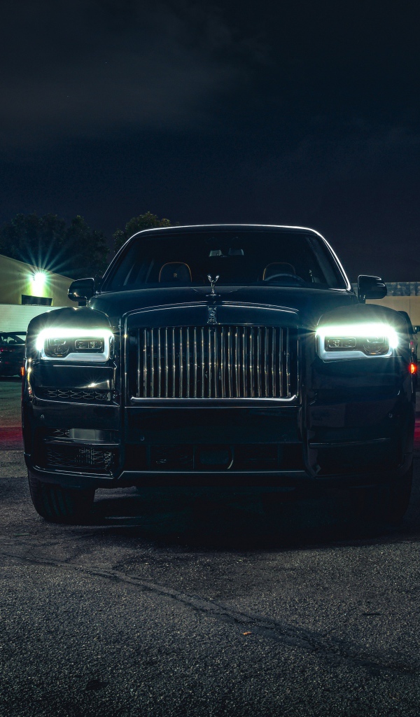 Черный дорогой автомобиль  Rolls-Royce Cullinan, 2020 года с включенными фарами