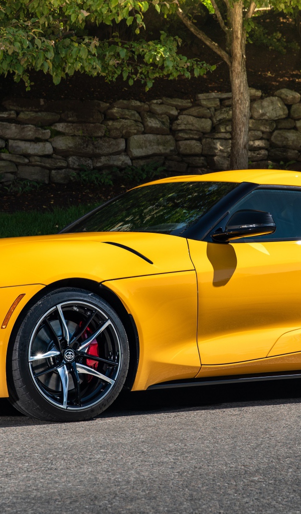 Желтый автомобиль Toyota GR Supra,ю 2021 года у стены