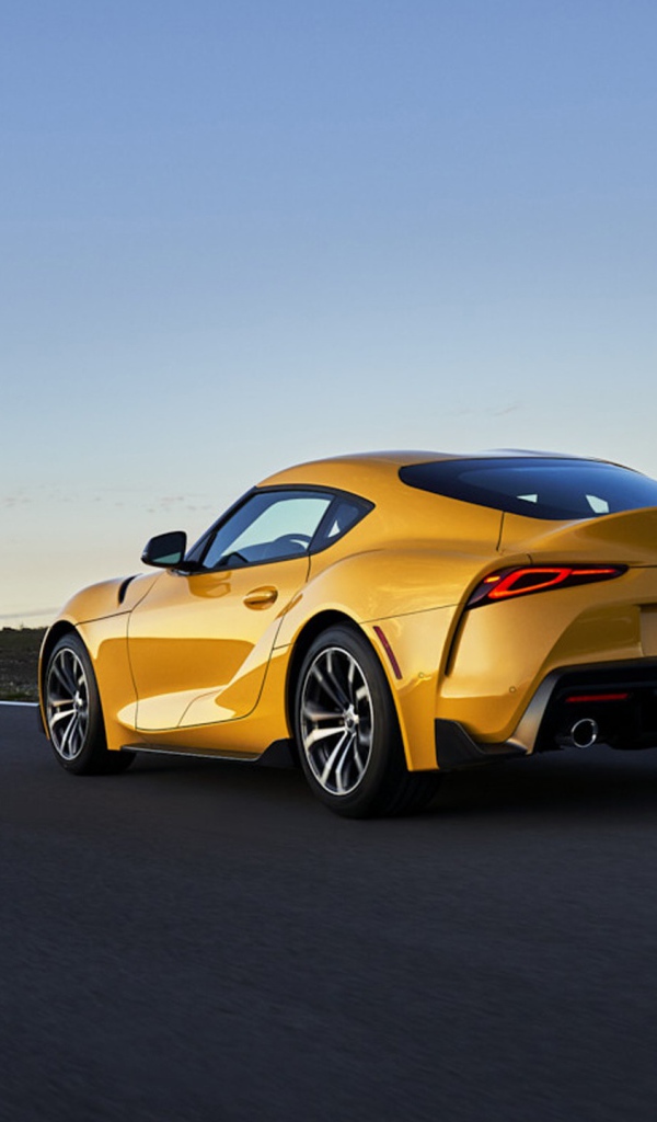 Желтый автомобиль Toyota GR Supra, 2021 года на трассе вид сзади