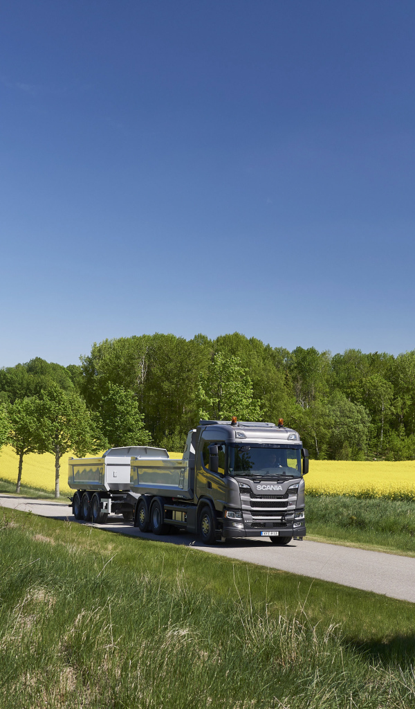 Грузовик Scania Trucks на трассе у поля