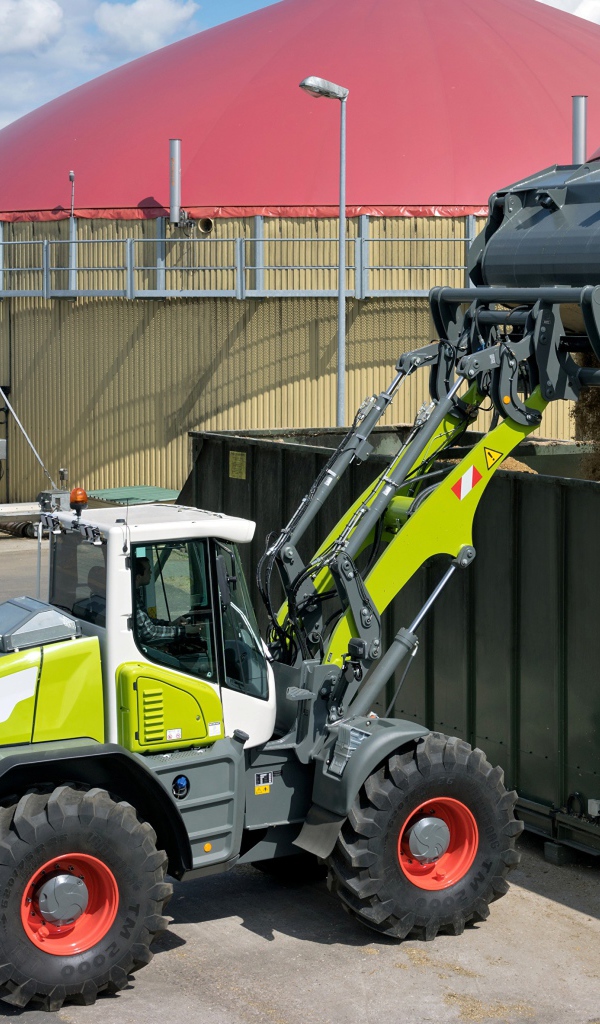 Трактор с ковшом высыпает песок в контейнеры 