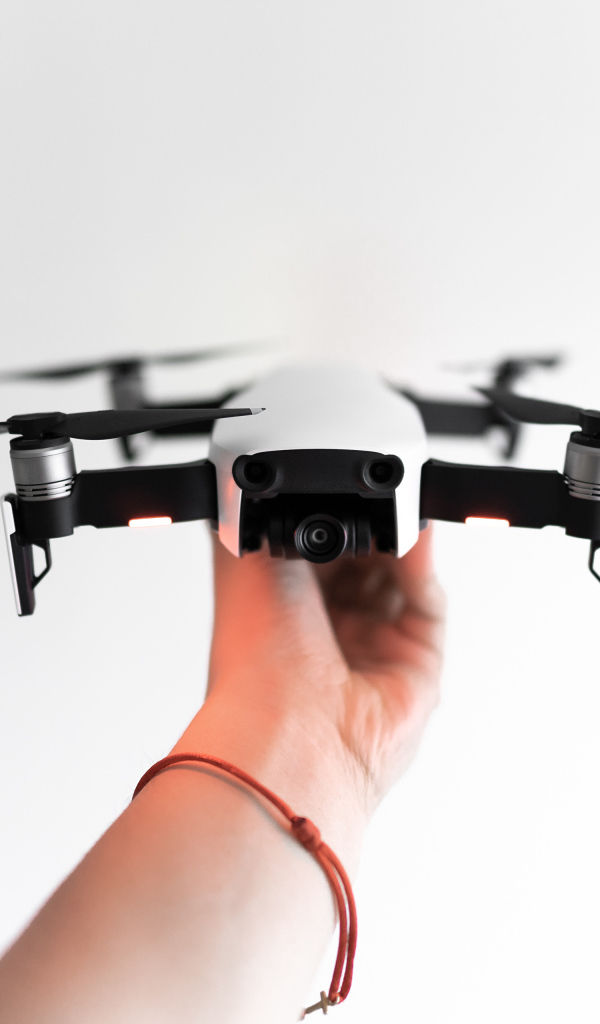 Белый квадрокоптер в руке на белом фоне