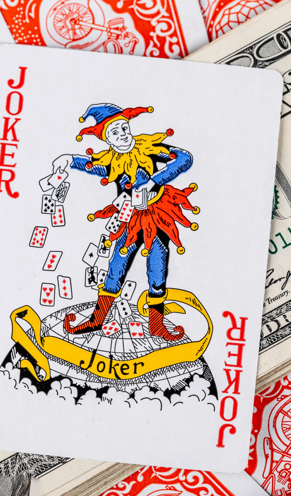 Карточный Джокер и пачка стодолларовых купюр