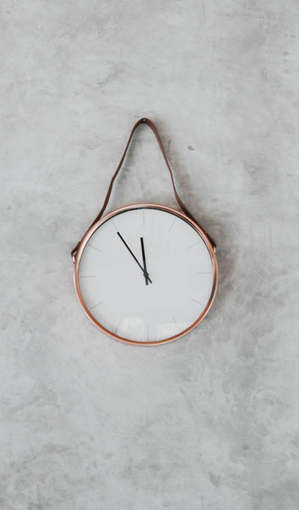 Часы с черными стрелками висят на серой стене 