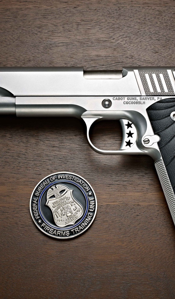 Пистолет Cabot 1911 лежит на столе с очками и жетоном 