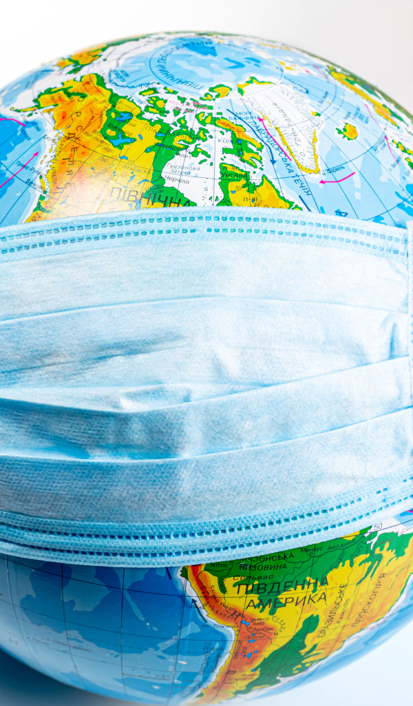 Руки одевают маску от коронавируса на глобус 