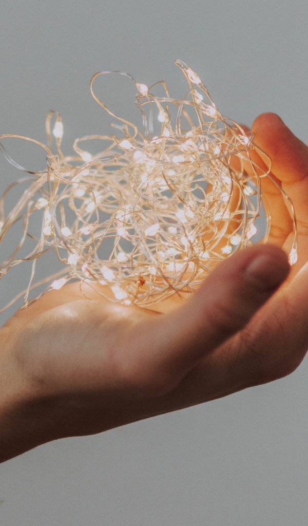 Включенная гирлянда в руке на сером фоне