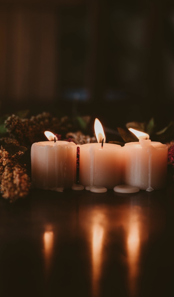 Зажженные свечи с цветами на полу