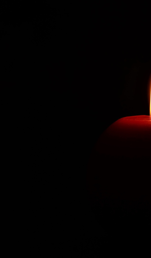 Lighted red candle on black background