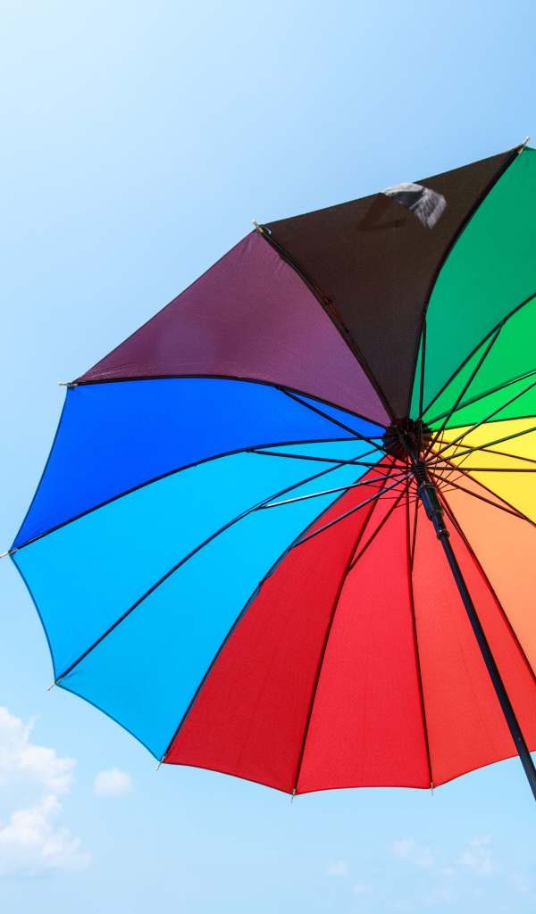 Разноцветный зонт на фоне голубого неба 