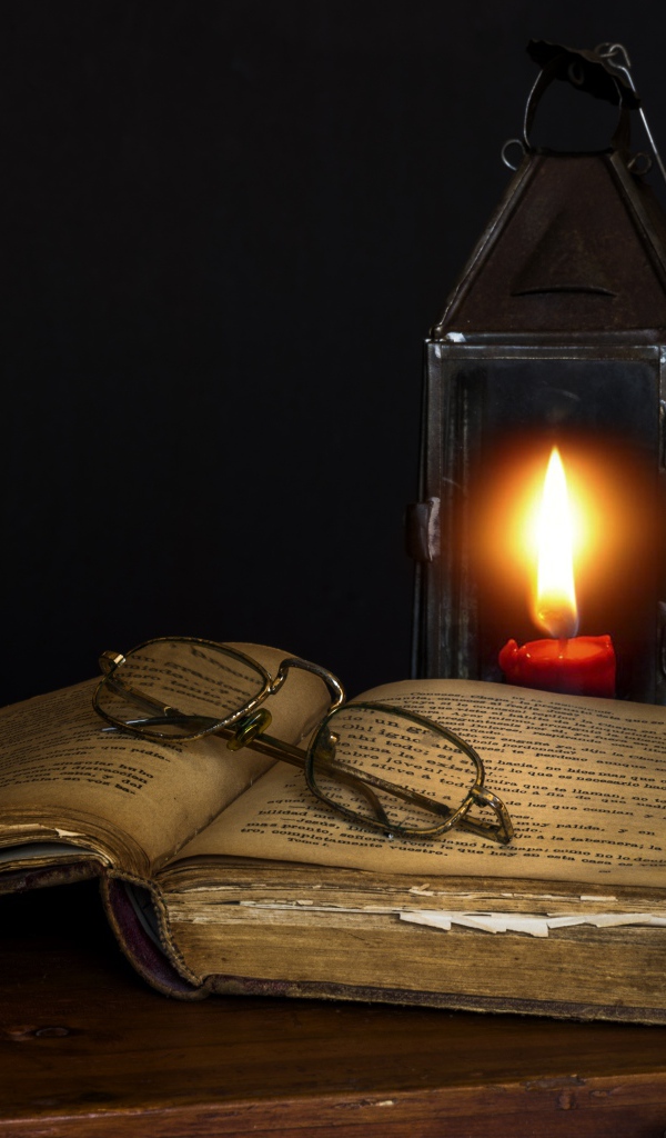 Старая книга на столе с очками и лампой