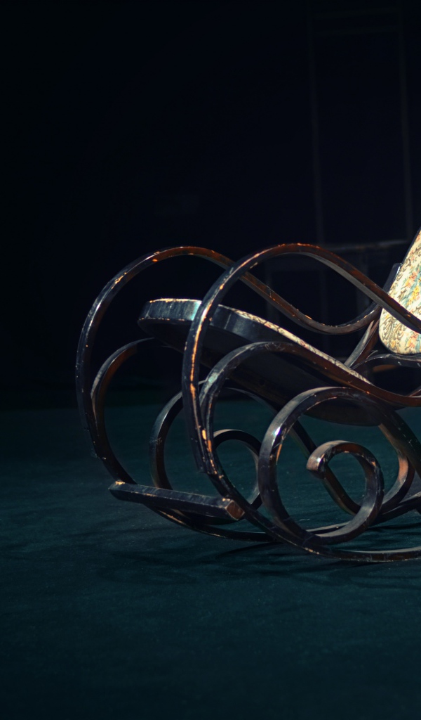 Старое кресло - качалка в темной комнате 