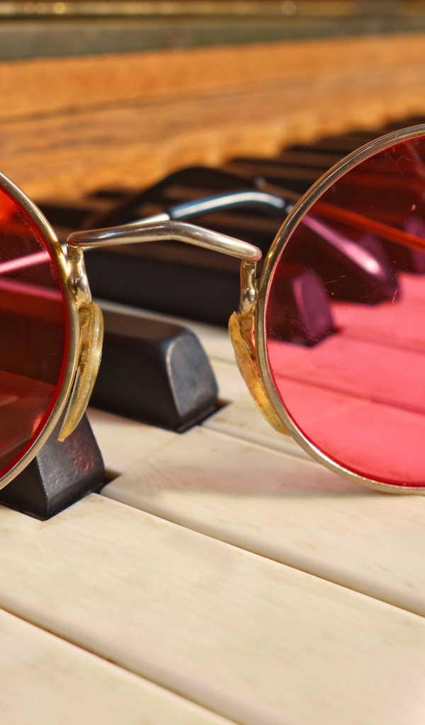 Розовые очки лежат на клавишах рояля