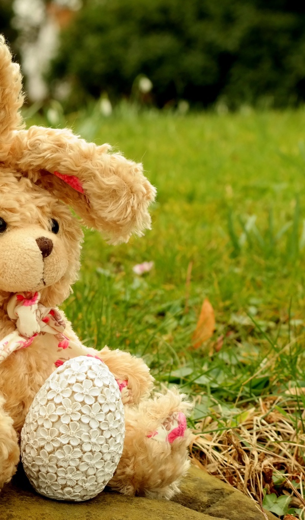 Игрушка заяц на камне в траве