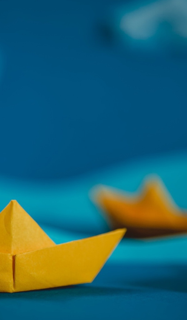 Желтые кораблики оригами на синем фоне