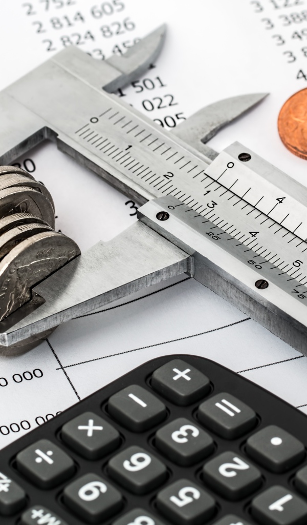 Монеты на столе с штангенциркулем и калькулятором