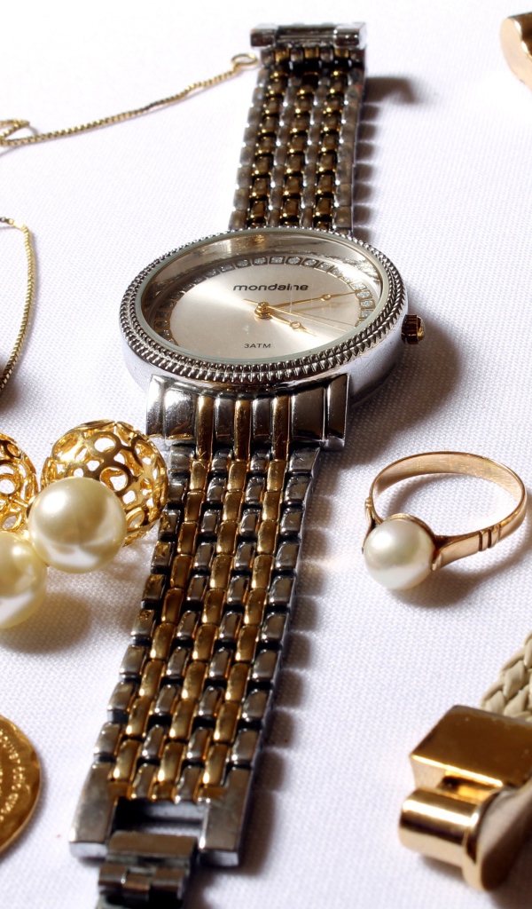 Наручные часы и золотые украшения на белом фоне