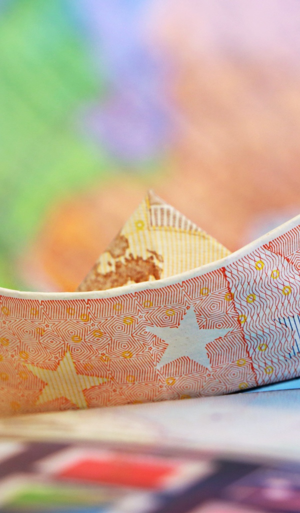 Кораблик из купюры евро на столе 