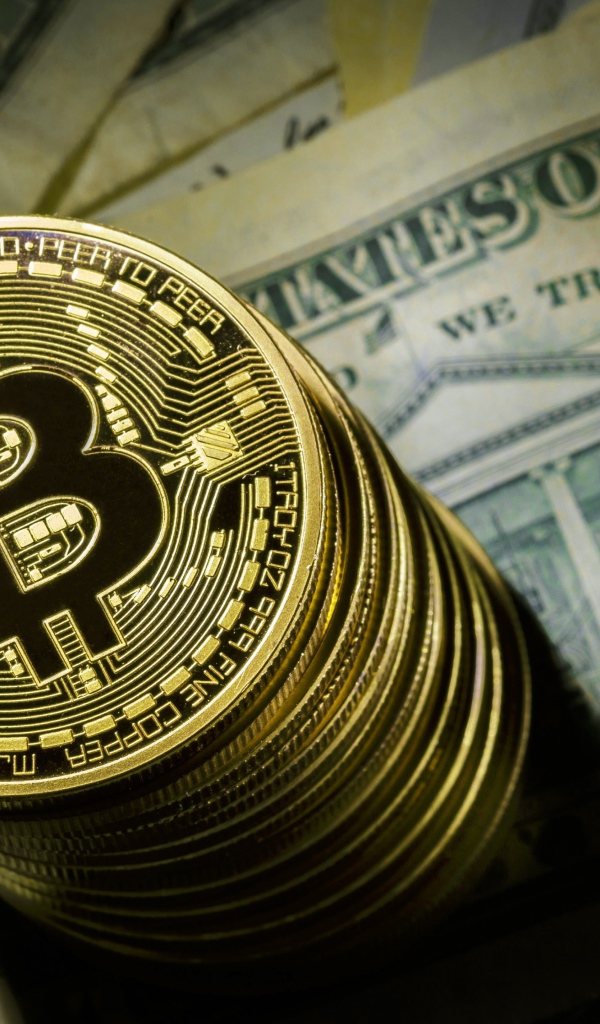 Золотые монеты биткоин лежат на долларах