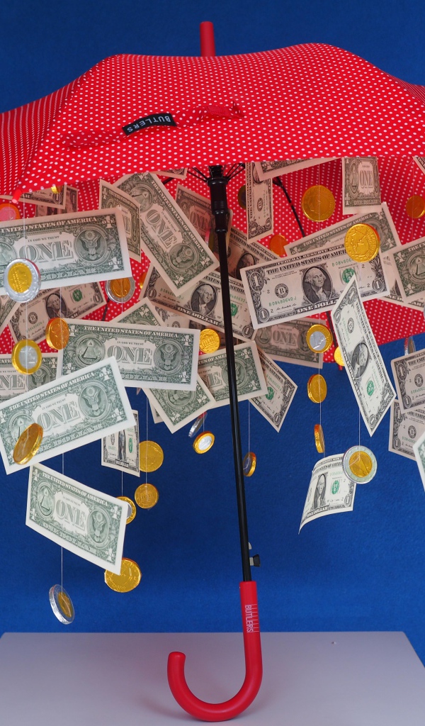 Доллары и монеты высыпаются из зонта на голубом фоне
