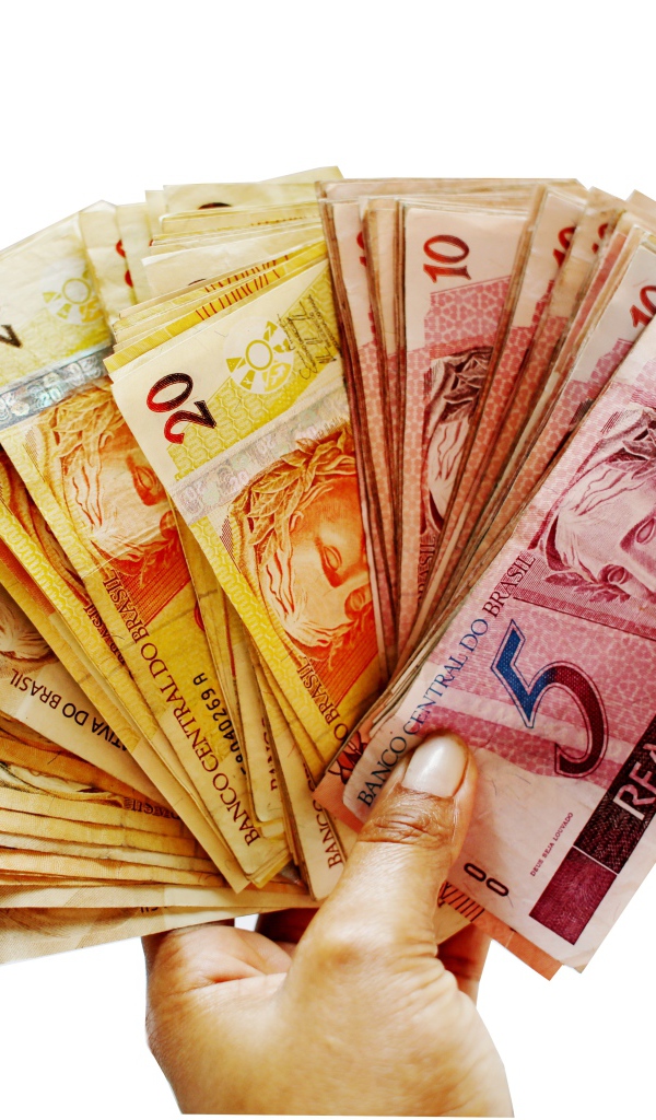 Много купюр бразильского реала в руке на белом фоне 